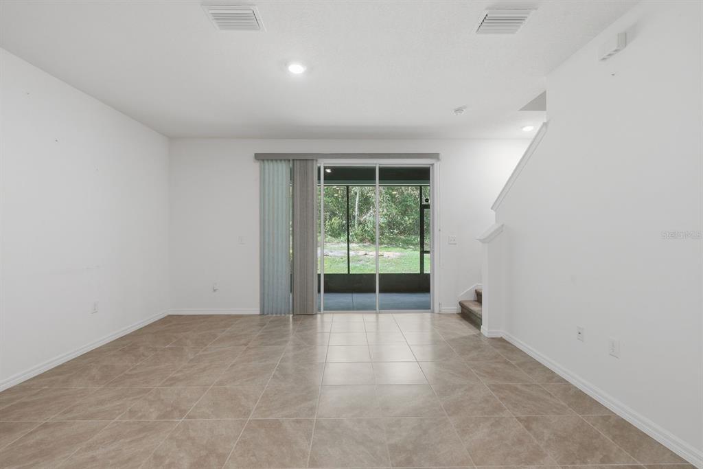 An empty room with tiled floors, white walls, and sliding glass doors leading to a patio — 13753 NW 9TH ROAD, NEWBERRY, FL