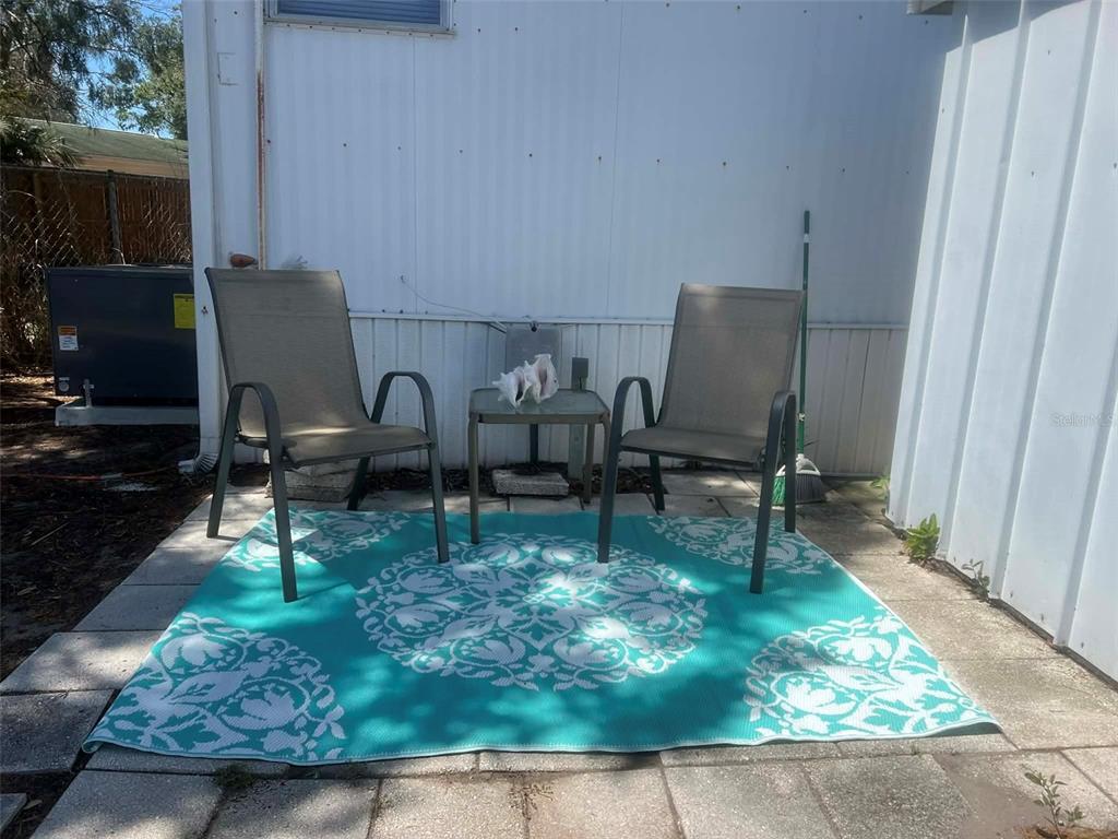 Two outdoor chairs and a small table sit on a patterned rug on a patio — 7801 34TH AVENUE N UNIT 88, ST PETERSBURG, FL