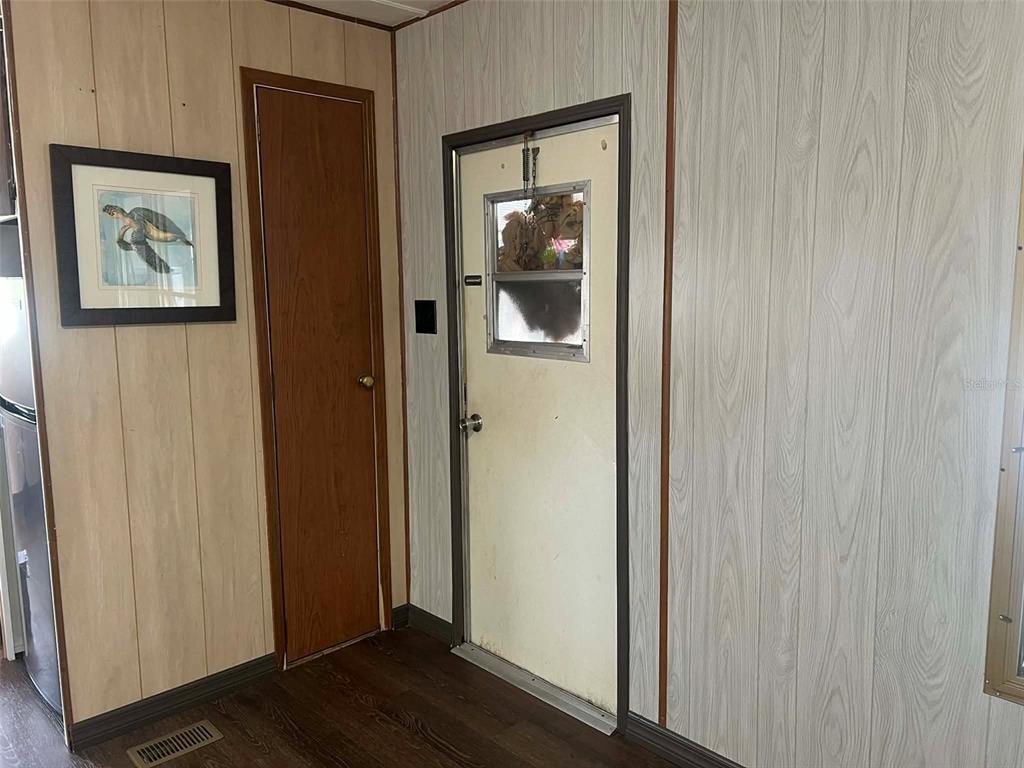 A room with wood-paneled walls, a dark wood door, and a white exterior door — 7801 34TH AVENUE N UNIT 88, ST PETERSBURG, FL