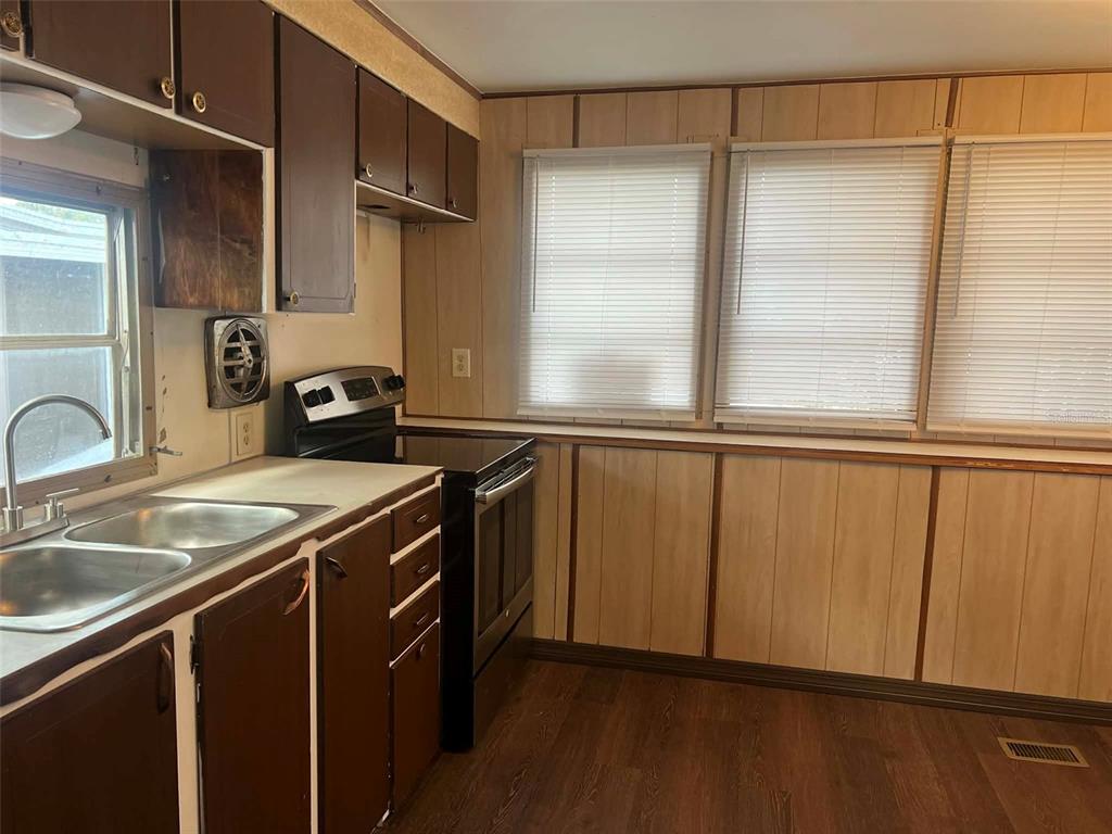 A kitchen features dark brown cabinets, a stainless steel sink, and wood-paneled walls — 7801 34TH AVENUE N UNIT 88, ST PETERSBURG, FL
