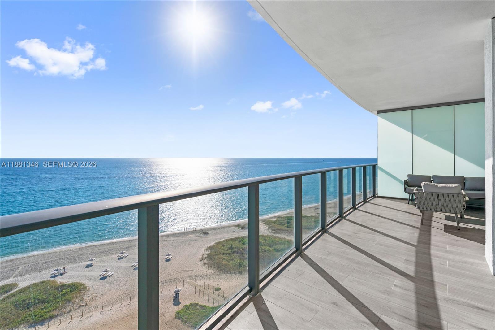 A balcony with a glass railing overlooks a sandy beach and the ocean — 1116 N Ocean Blvd # 1404, Pompano Beach FL 33062, POMPANO BEACH, FL
