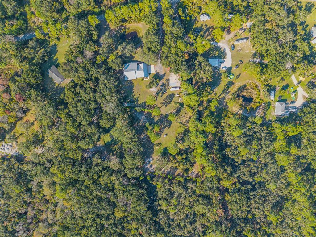 An aerial view shows several houses and outbuildings situated on a large, wooded lot — 0 CLINTON CEMETERY RD., EDGEWATER, FL