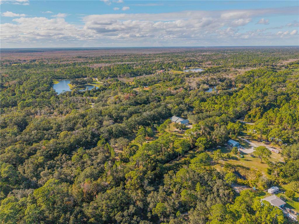 An aerial view shows a rural property with a house, outbuildings, and surrounding forest — 0 CLINTON CEMETERY RD., EDGEWATER, FL