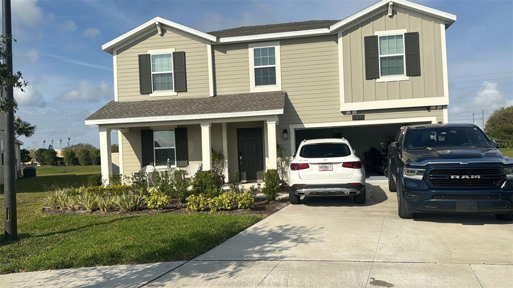 A two-story house with light green siding, a front porch, and a two-car garage — 4499 MAGNOLIA RIDGE COURT, KISSIMMEE, FL