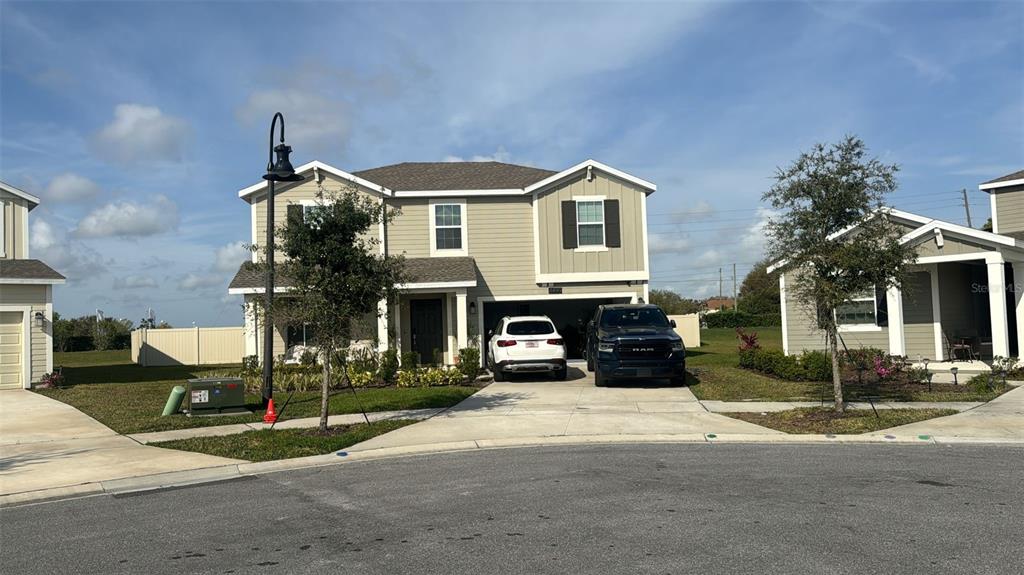A two-story suburban house with a tan exterior, a two-car garage, and a driveway — 4499 MAGNOLIA RIDGE COURT, KISSIMMEE, FL