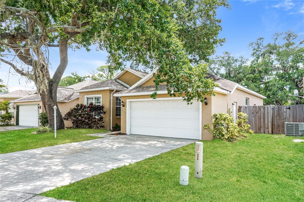 A tan single-story house with a white garage door, driveway, and large oak tree — 1840 SUMMER WALK CIRCLE, SARASOTA, FL