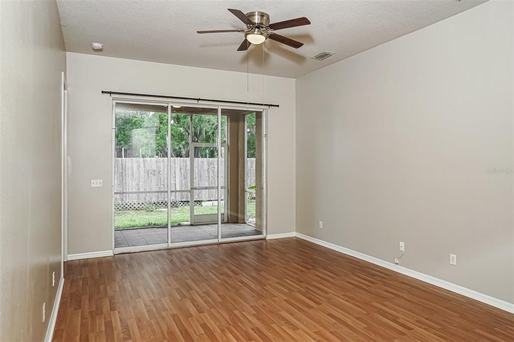 An empty room with wood-look flooring, a ceiling fan, and sliding glass doors to a patio — 1840 SUMMER WALK CIRCLE, SARASOTA, FL