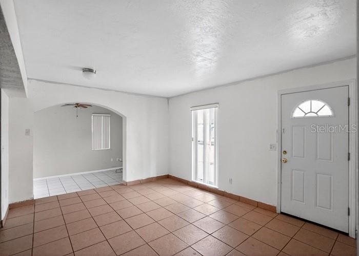 A room with tiled floors, white walls, an arched entryway, and a white front door — 1668 W WAYCROSS CIRCLE, DELTONA, FL