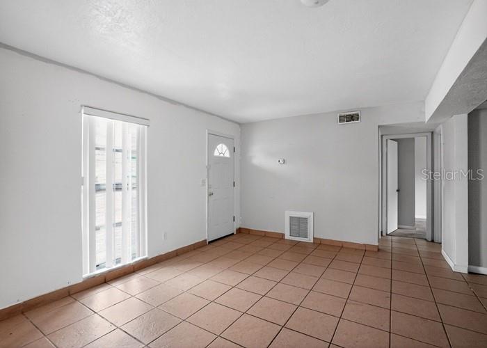 A room with white walls, tiled floors, a window with vertical blinds, and two doorways — 1668 W WAYCROSS CIRCLE, DELTONA, FL