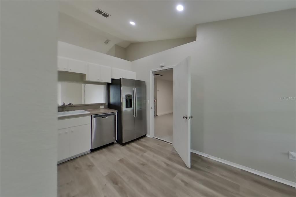 A kitchen with stainless steel appliances, white cabinets, and light wood-look flooring — 3034 WENTWORTH PLACE, LAKELAND, FL