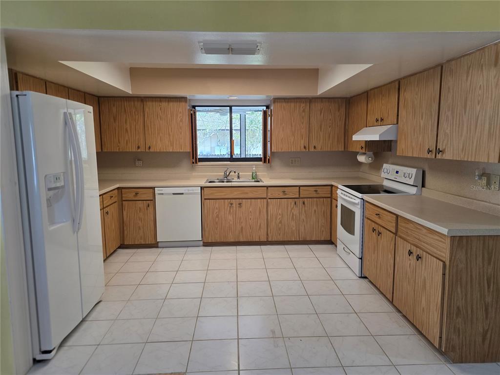 A dining area with wood-look flooring sits beneath a wooden staircase and a loft balcony — 4841 SUNDAY COURT, SARASOTA, FL