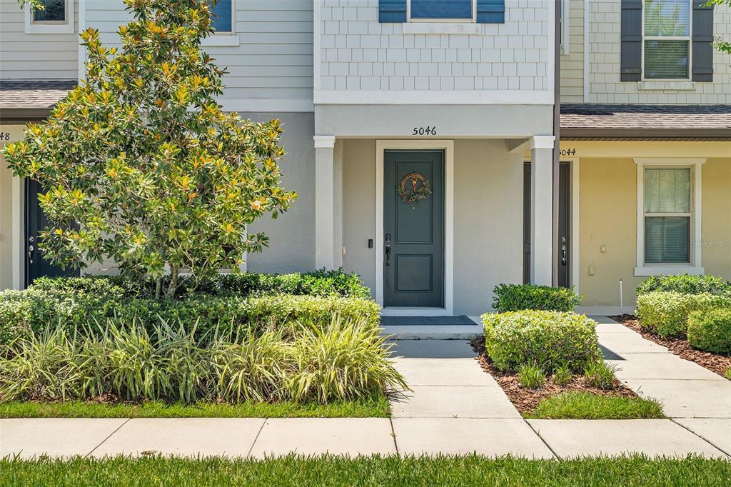 The exterior of a multi-story townhouse features a dark front door and landscaped front yard — 5046 WALKER STREET, ST CLOUD, FL