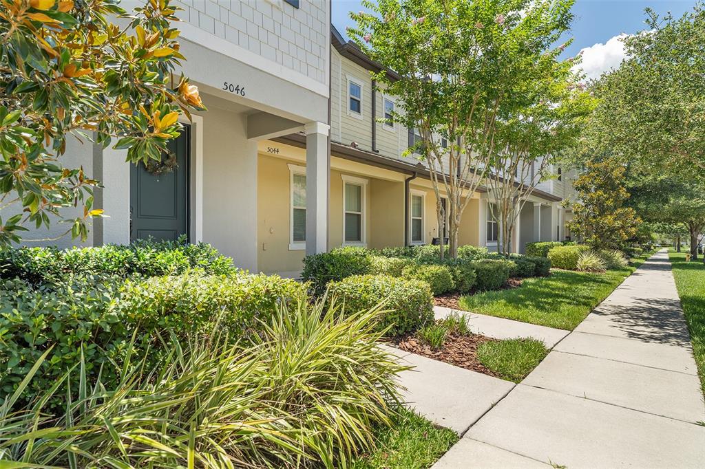 A row of townhouses features beige siding, covered entryways, and a sidewalk along the front — 5046 WALKER STREET, ST CLOUD, FL