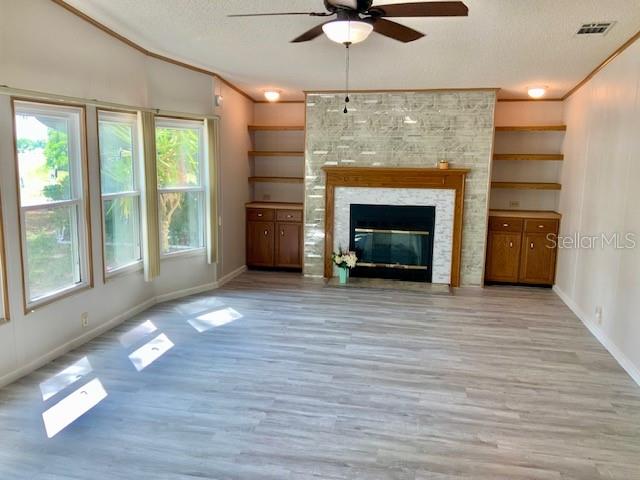 A living room features a fireplace with a stone surround, built-in shelving, and light wood flooring — 13957 COUNTY ROAD 109D, LADY LAKE, FL