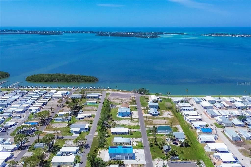 An aerial view shows a coastal neighborhood with mobile homes situated along a blue bay — 4515 106TH STREET W, BRADENTON, FL