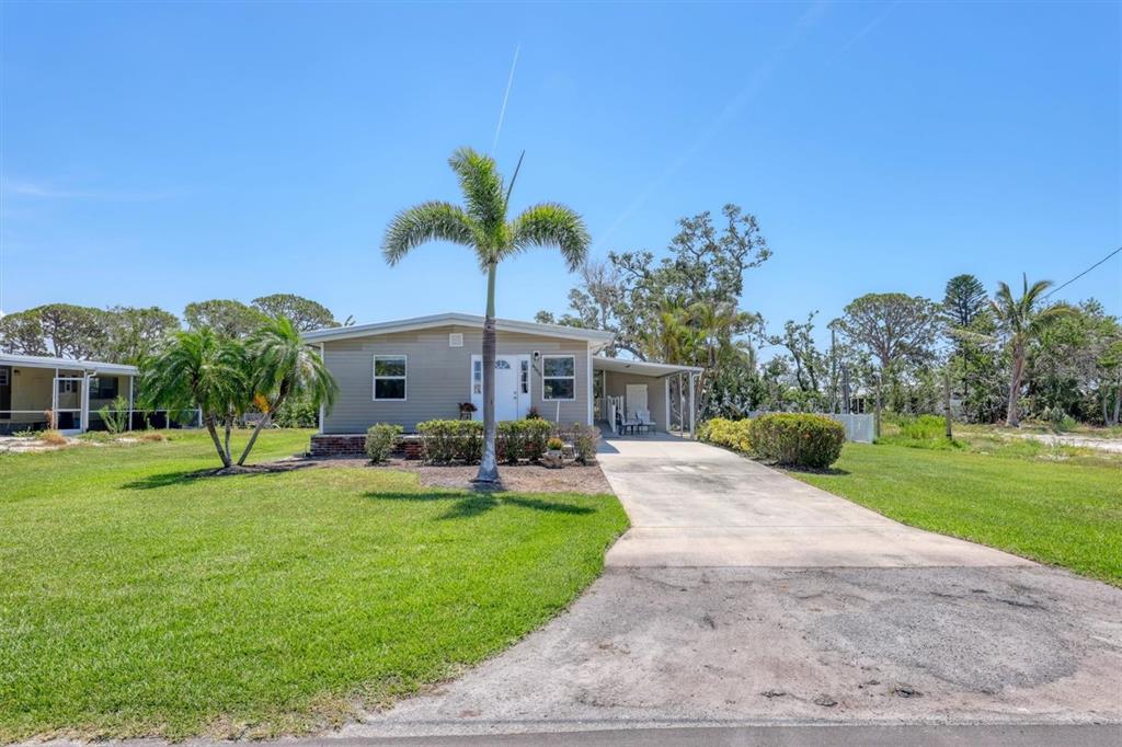 A single-story house with light siding, a concrete driveway, and a palm tree in front — 4515 106TH STREET W, BRADENTON, FL
