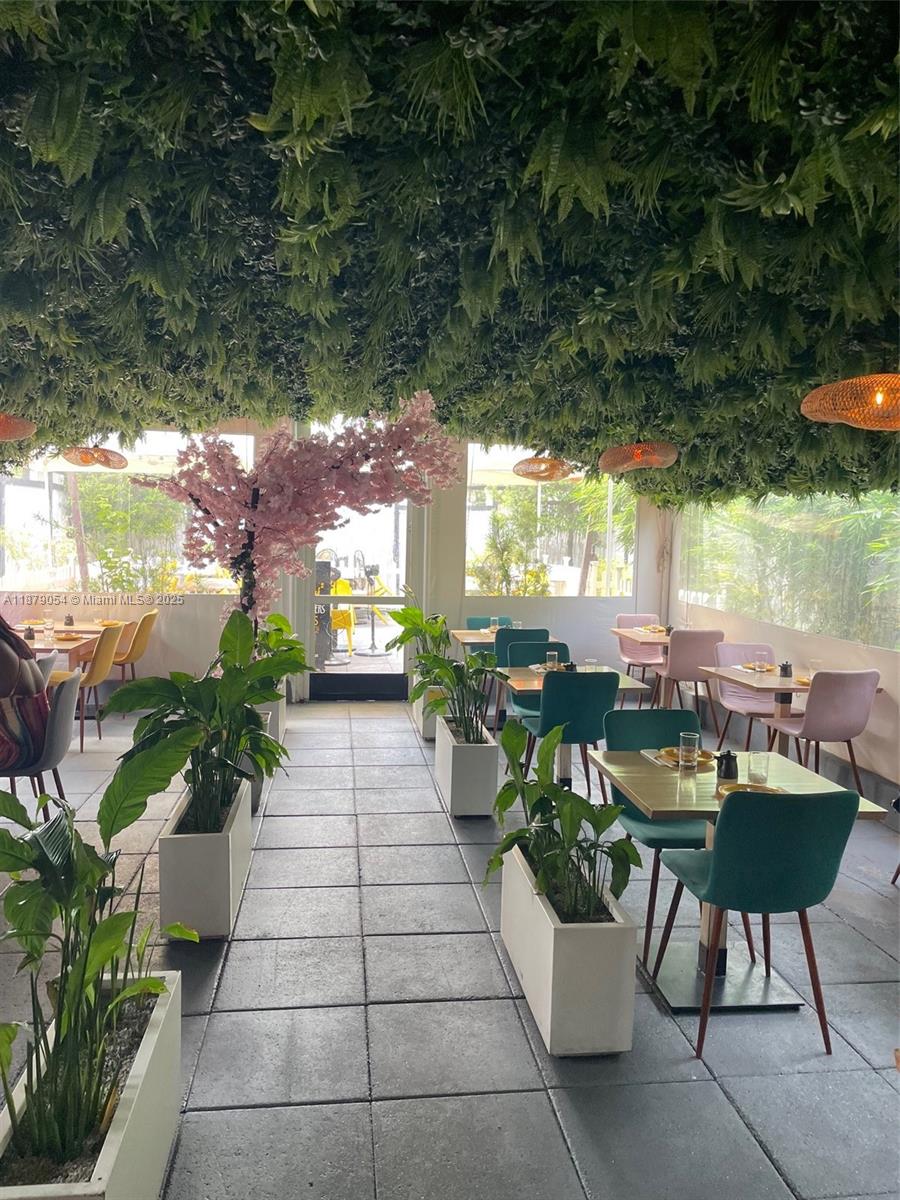 A restaurant dining area features a ceiling covered in greenery, a cherry blossom tree, and tables — 7228 Biscayne Blvd, Miami FL 33138, MIAMI, FL