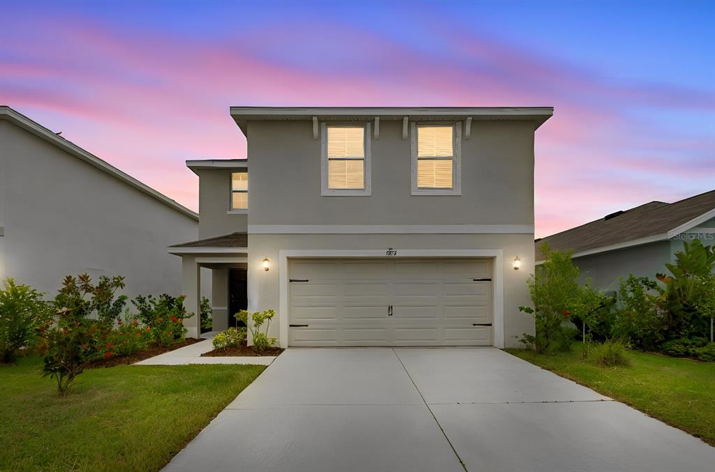 A two-story suburban house features a two-car garage, light-colored stucco siding, and a concrete driveway — 5254 ROCKY COAST PLACE, PALMETTO, FL