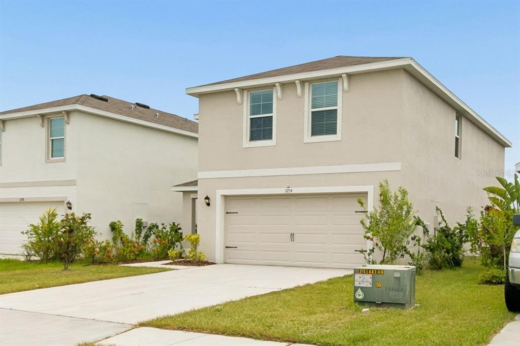 A two-story suburban house with a beige stucco exterior and a two-car garage — 5254 ROCKY COAST PLACE, PALMETTO, FL