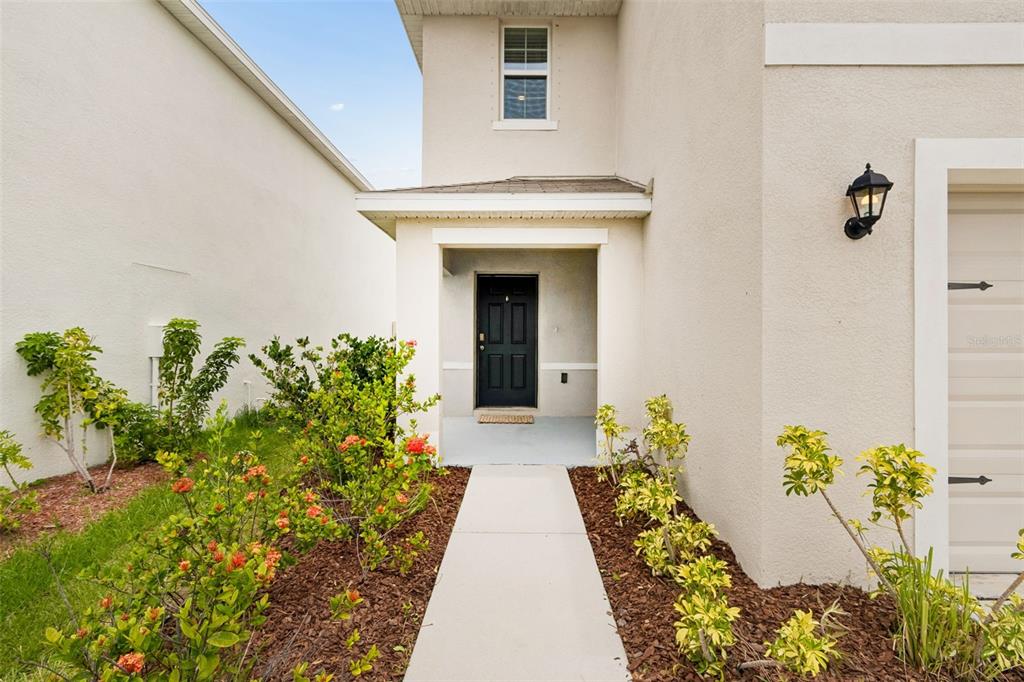A concrete walkway leads to the black front door of a beige two-story house — 5254 ROCKY COAST PLACE, PALMETTO, FL