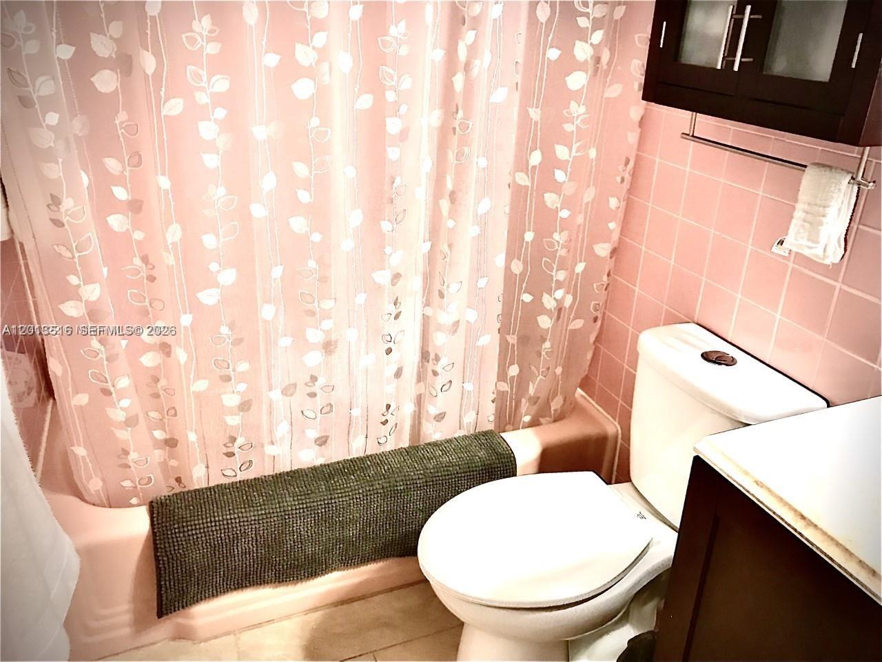 A bathroom features pink tiled walls, a white toilet, and a leaf-patterned shower curtain — 900 SW 11th Ave # 17C, Hallandale Beach FL 33009, HALLANDALE BEACH, FL