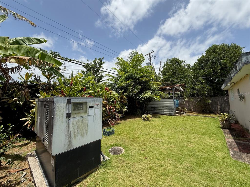 A backyard features a large generator, a small shed, and lush tropical landscaping — 1771 ALCALÁ, SAN JUAN, PR