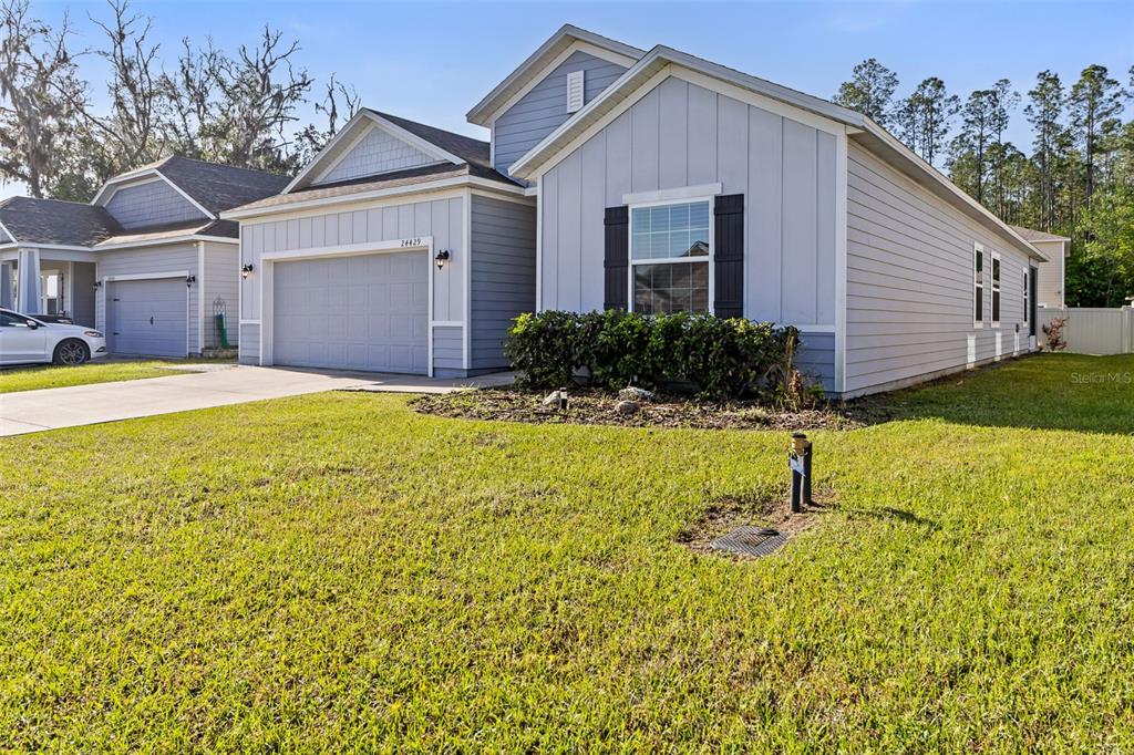 A light blue single-story house with a two-car garage and a front lawn — 24429 NW 7TH LANE, NEWBERRY, FL