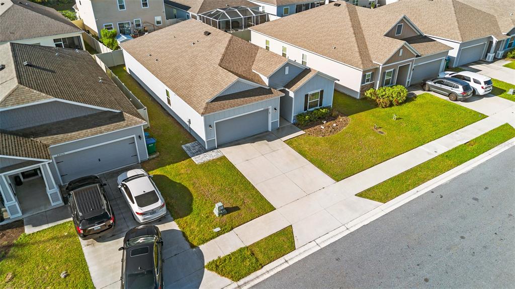 An aerial view shows suburban houses with driveways, parked cars, and manicured lawns — 24429 NW 7TH LANE, NEWBERRY, FL