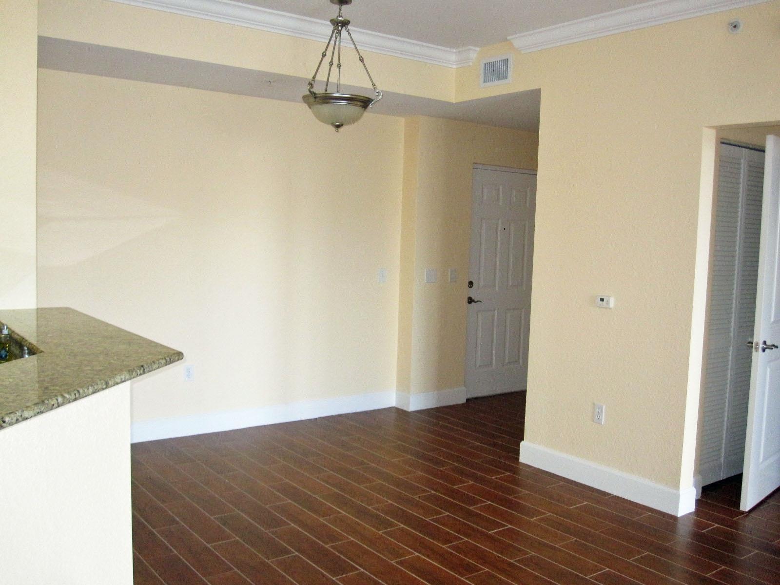 An empty dining area features light yellow walls, dark wood-look tile flooring, and a chandelier — 1690 Renaissance Commons Boulevard # 1629, Boynton Beach FL 33426, BOYNTON BEACH, FL