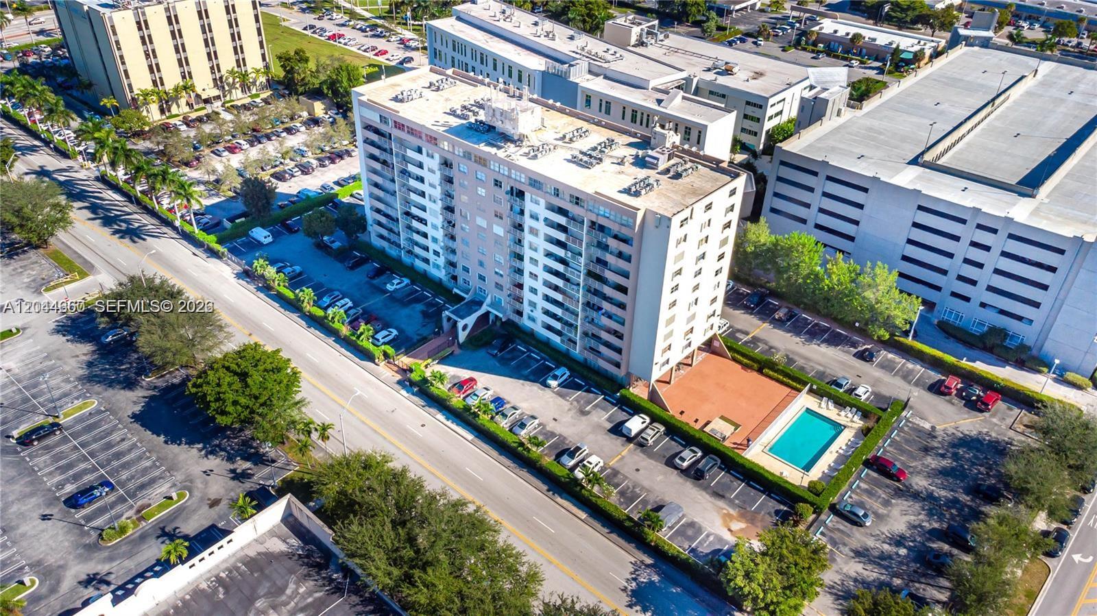 An aerial view shows a multi-story apartment building with a swimming pool and parking lots — HIALEAH, FL