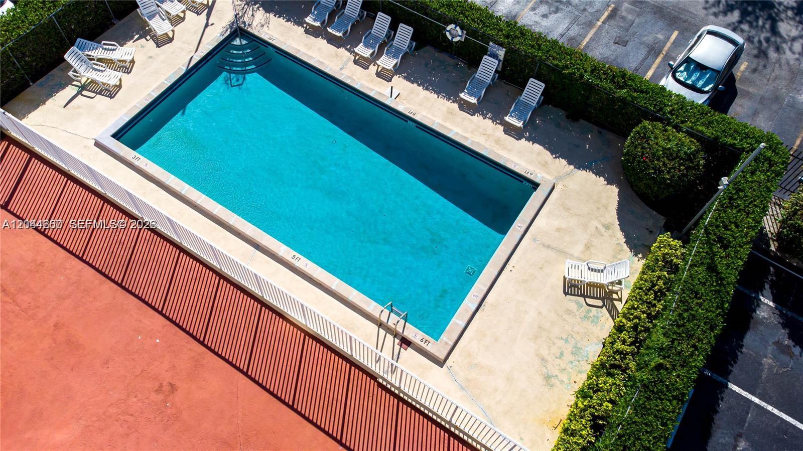 An aerial view shows a rectangular swimming pool surrounded by lounge chairs and hedges — HIALEAH, FL