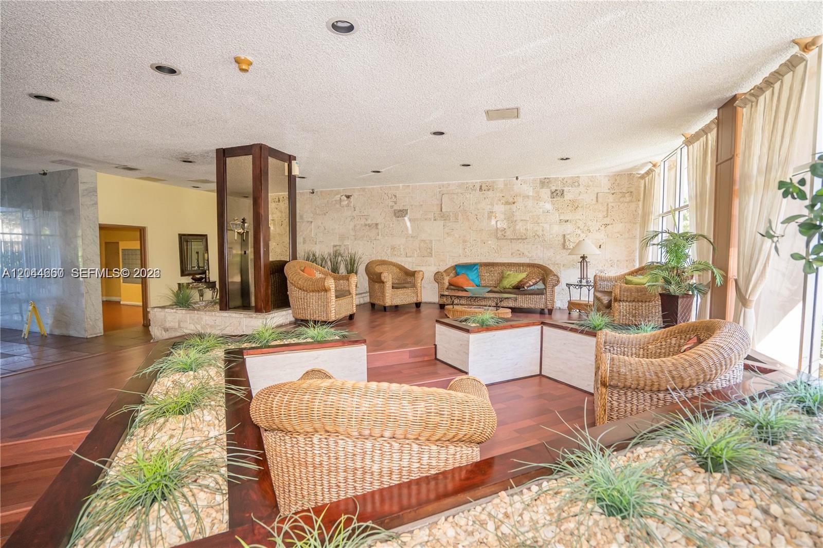 A lobby features wicker furniture, a stone accent wall, and a sunken seating area — HIALEAH, FL