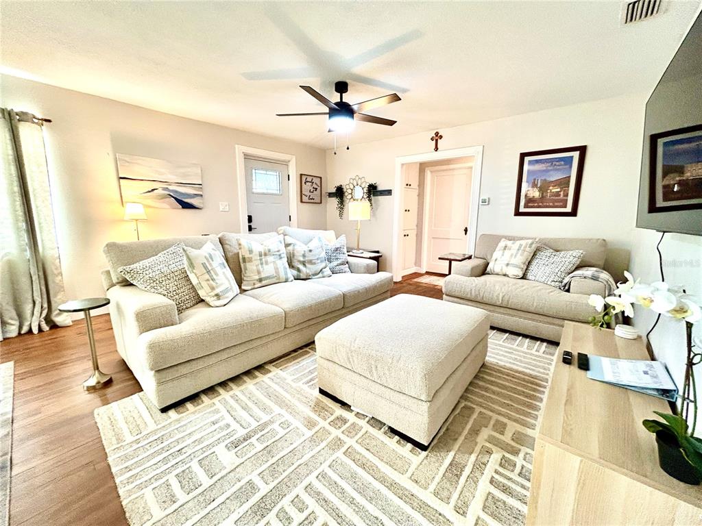 A living room features a light-colored sofa, matching ottoman, area rug, and ceiling fan — 265 W BAY AVENUE, LONGWOOD, FL