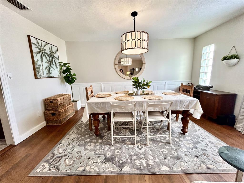 A dining room features a wooden table with a white tablecloth, a rug, and a chandelier — 265 W BAY AVENUE, LONGWOOD, FL