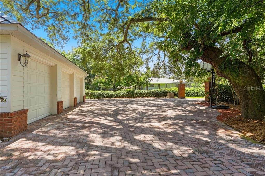 A brick-paved driveway leads to a three-car garage under a large, mature oak tree — 1645 CRUMP ROAD, WINTER HAVEN, FL
