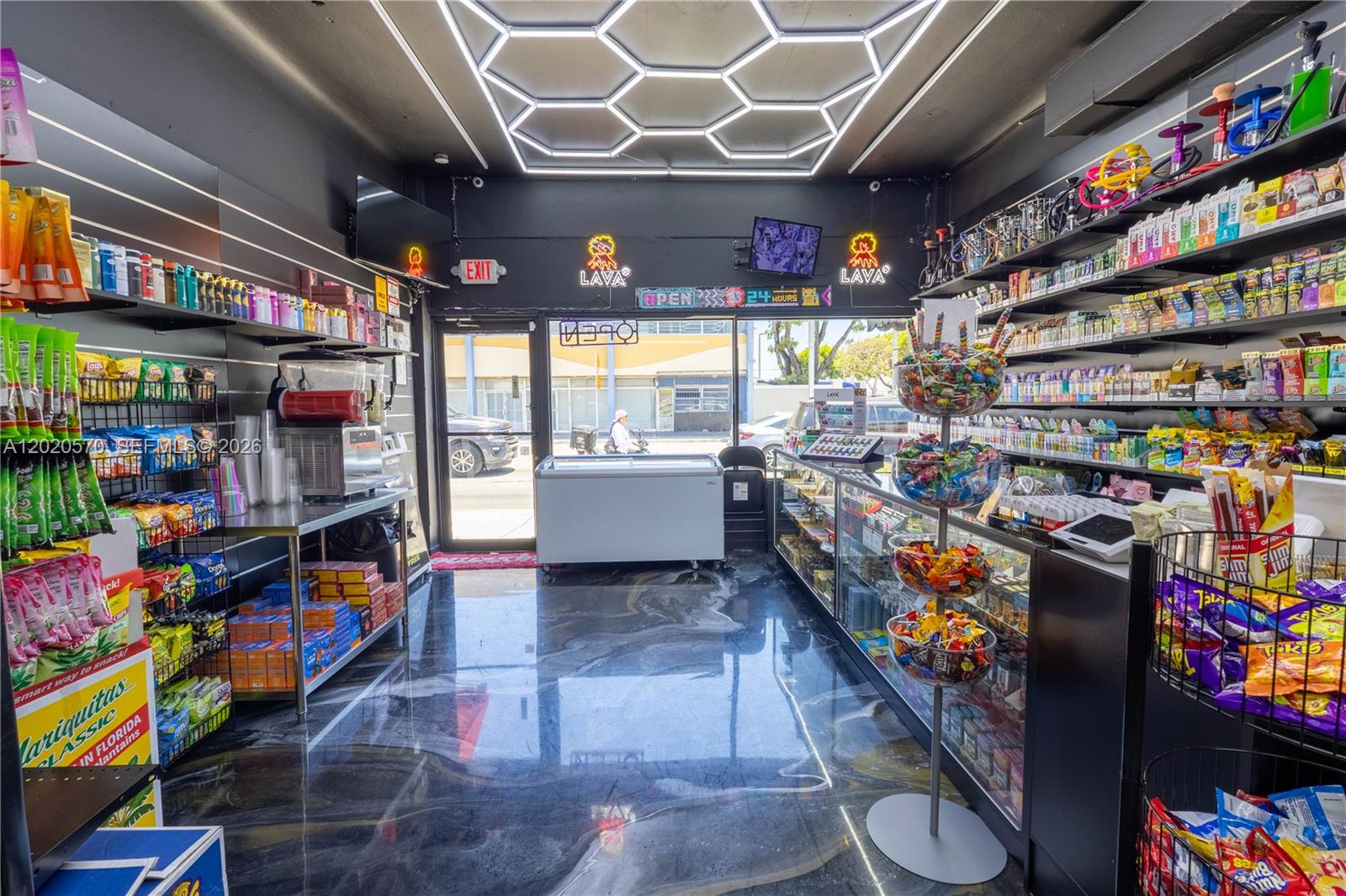 A retail shop interior features shelves of snacks, a glass display case, and hexagonal ceiling lights — 2607 Flagler St, Miami FL 33135, MIAMI, FL
