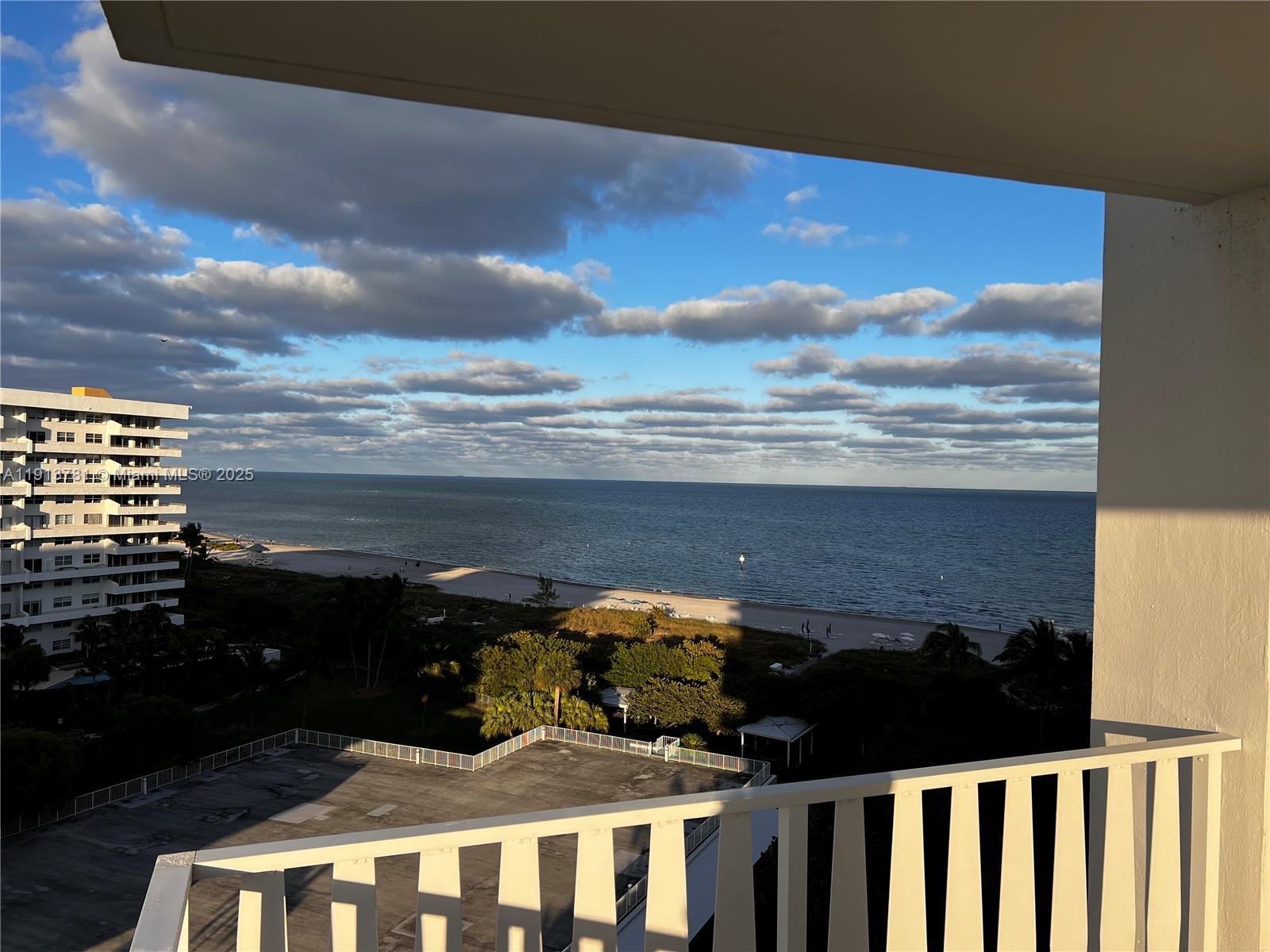 A balcony view overlooks a beach, the ocean, and a nearby high-rise building — 200 Ocean Lane Dr # 909, Key Biscayne FL 33149, KEY BISCAYNE, FL