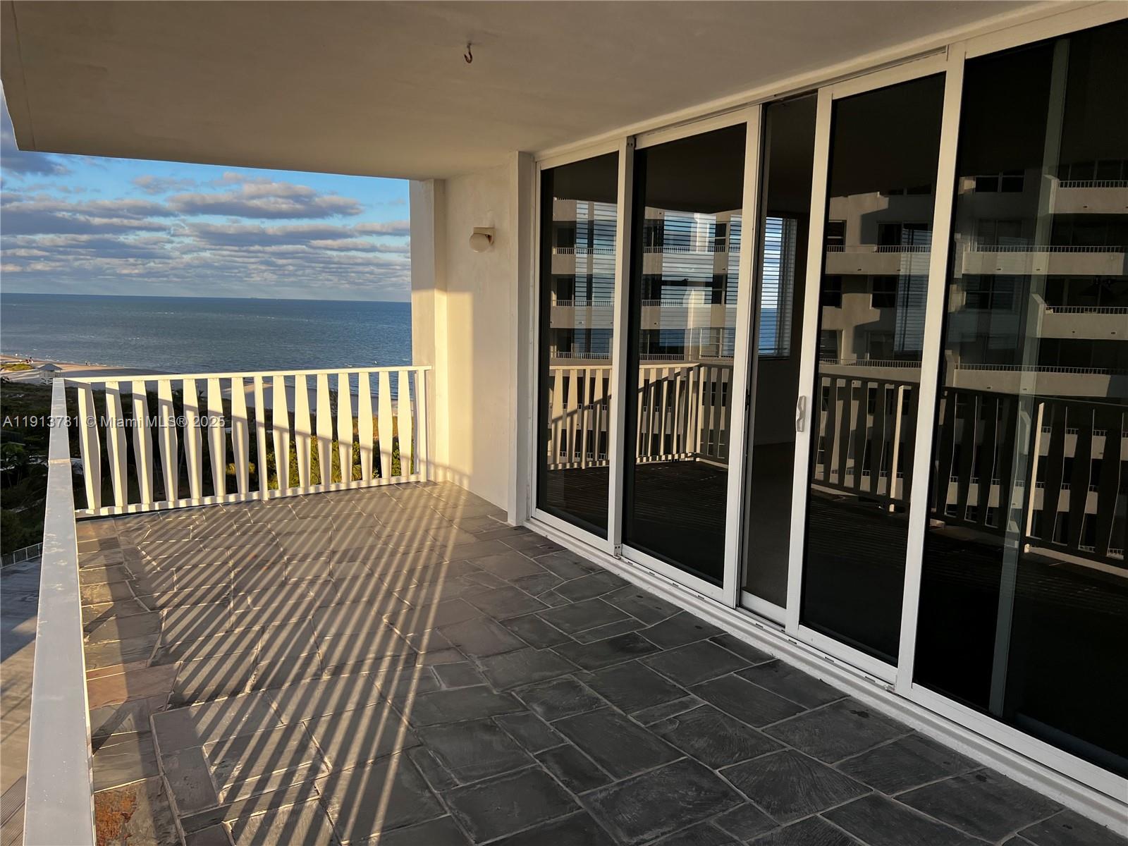 A balcony with stone tile flooring overlooks the ocean and features sliding glass doors — 200 Ocean Lane Dr # 909, Key Biscayne FL 33149, KEY BISCAYNE, FL