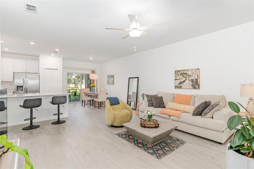 An open-concept living and dining area features light wood-look tile flooring and a kitchen island — 710 NW 126TH TERRACE, NEWBERRY, FL