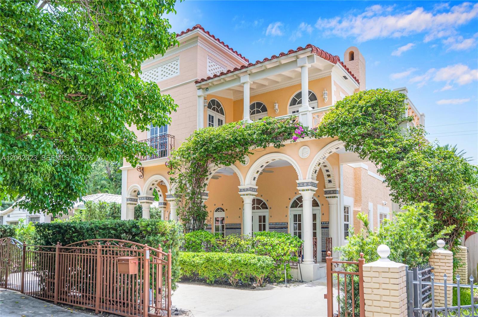 A three-story Mediterranean-style house features arched entryways, a second-floor balcony, and lush landscaping — 30 NE 44th St, Miami FL 33137, MIAMI, FL