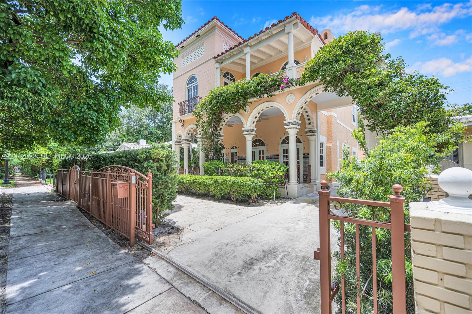 A three-story Mediterranean-style house features arched columns, a balcony, and a gated concrete driveway — 30 NE 44th St, Miami FL 33137, MIAMI, FL