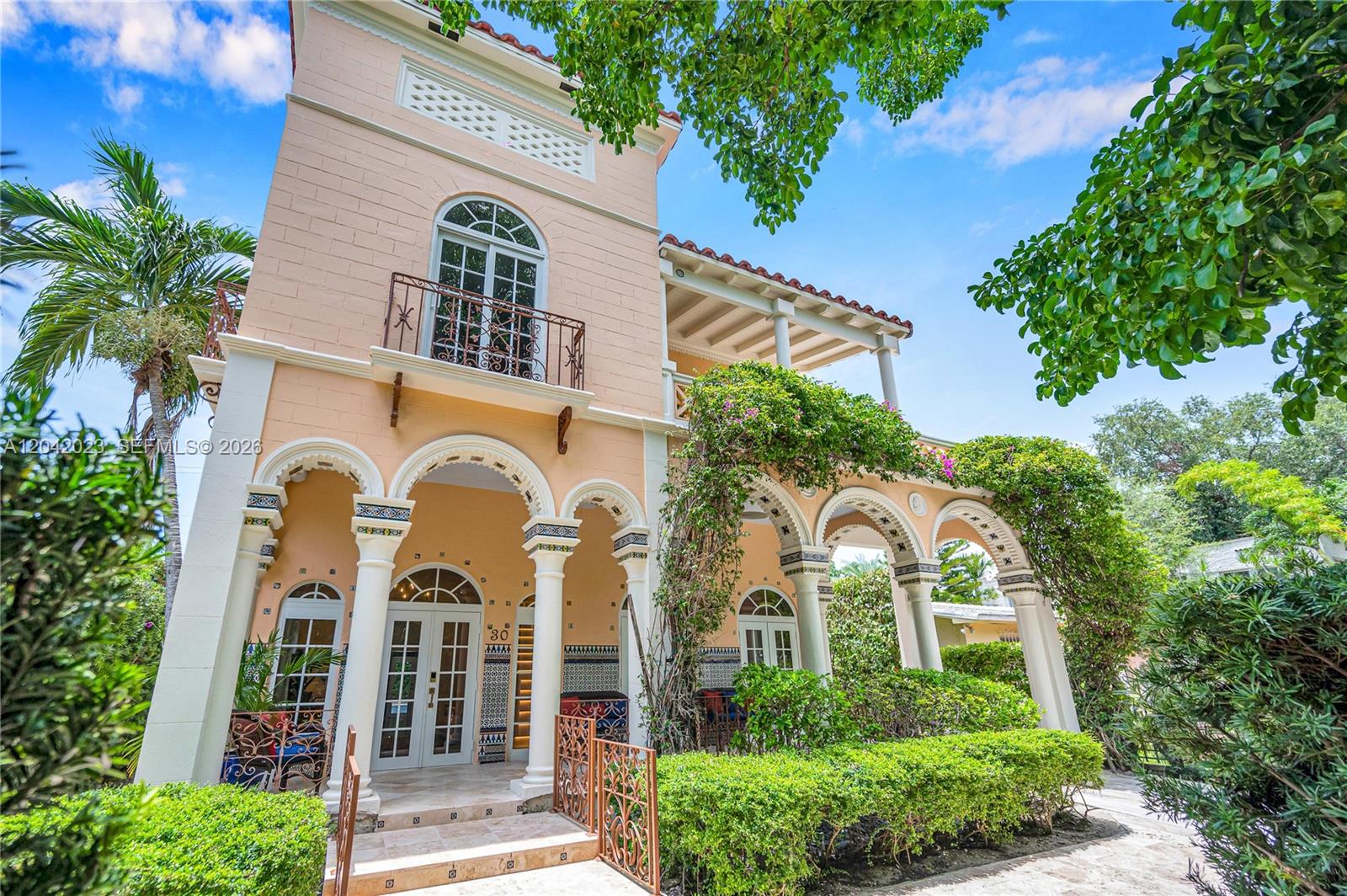 A Mediterranean-style house features a peach-colored exterior, arched columns, a balcony, and lush landscaping — 30 NE 44th St, Miami FL 33137, MIAMI, FL