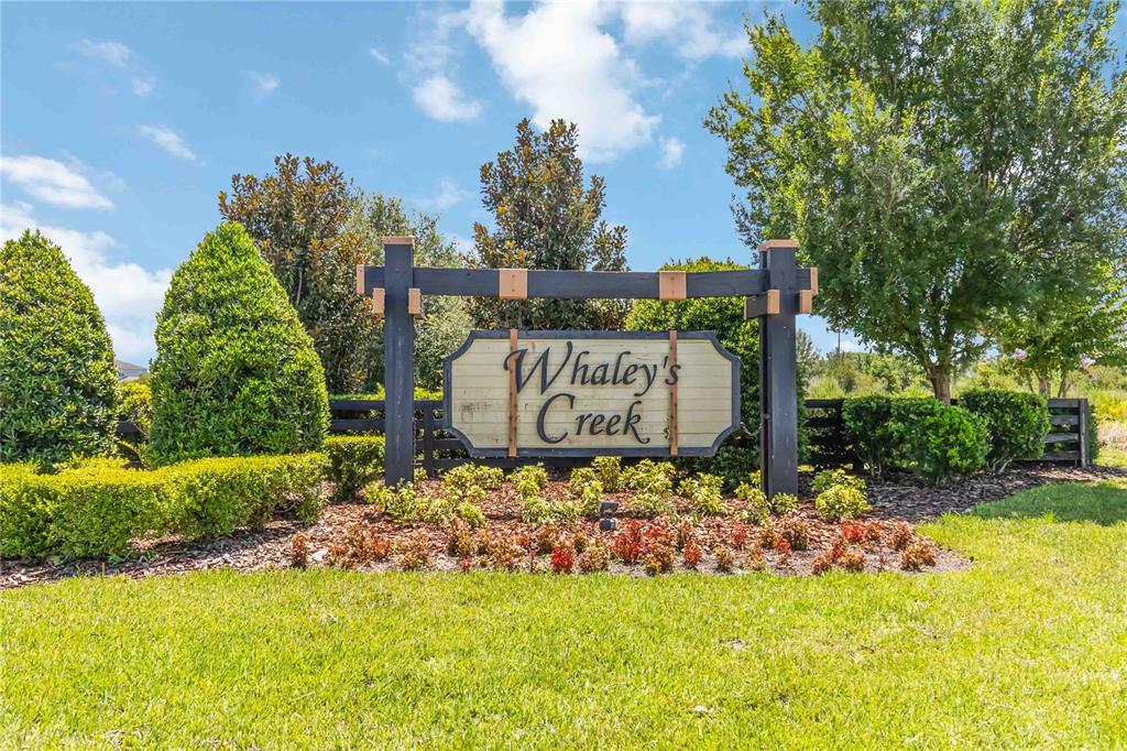 A wooden neighborhood entrance sign for Whaley's Creek stands in a landscaped garden — 3900 BAJA DRIVE, ST CLOUD, FL