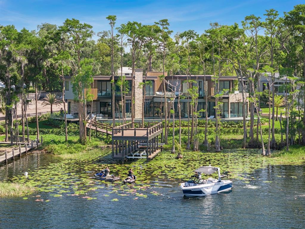 A modern multi-story house sits on a lakefront lot with a wooden dock and boat — 728 FOREST STREET, WINDERMERE, FL