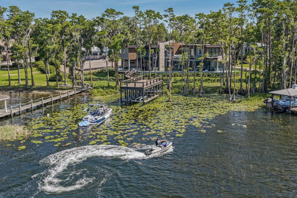 An aerial view of a modern house on a lake with a dock and boats — 728 FOREST STREET, WINDERMERE, FL