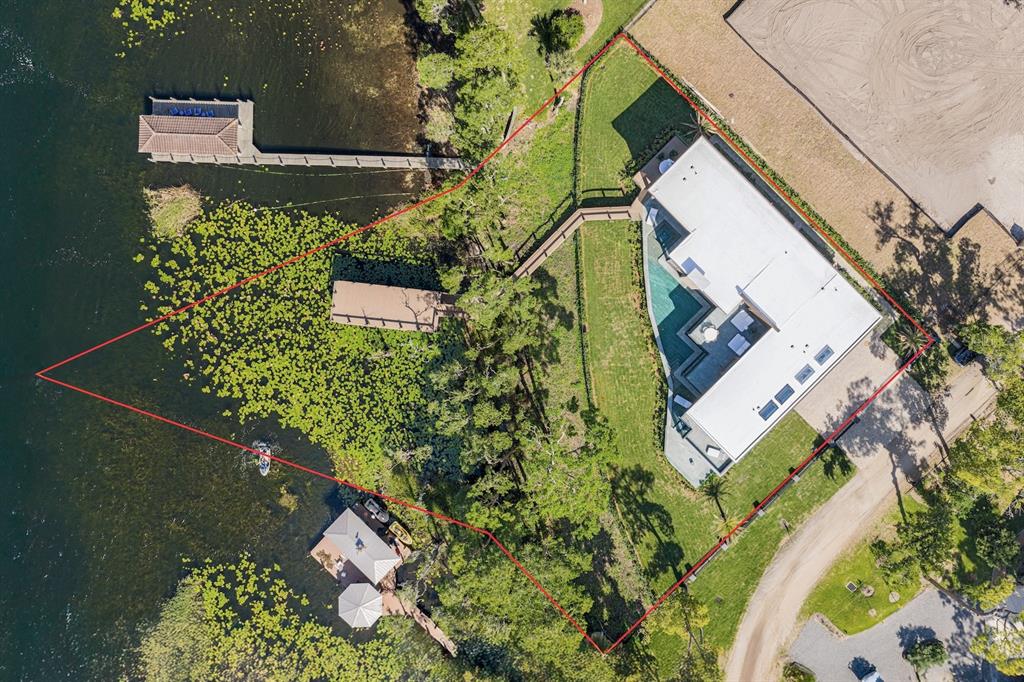 An aerial view shows a waterfront house with a pool, dock, and boathouse — 728 FOREST STREET, WINDERMERE, FL