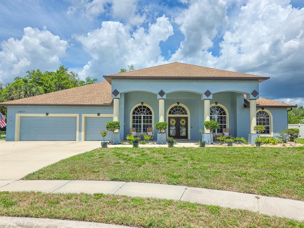 A blue, single-story house with a three-car garage and a columned front porch — 6053 SABAL CREEK BOULEVARD, PORT ORANGE, FL