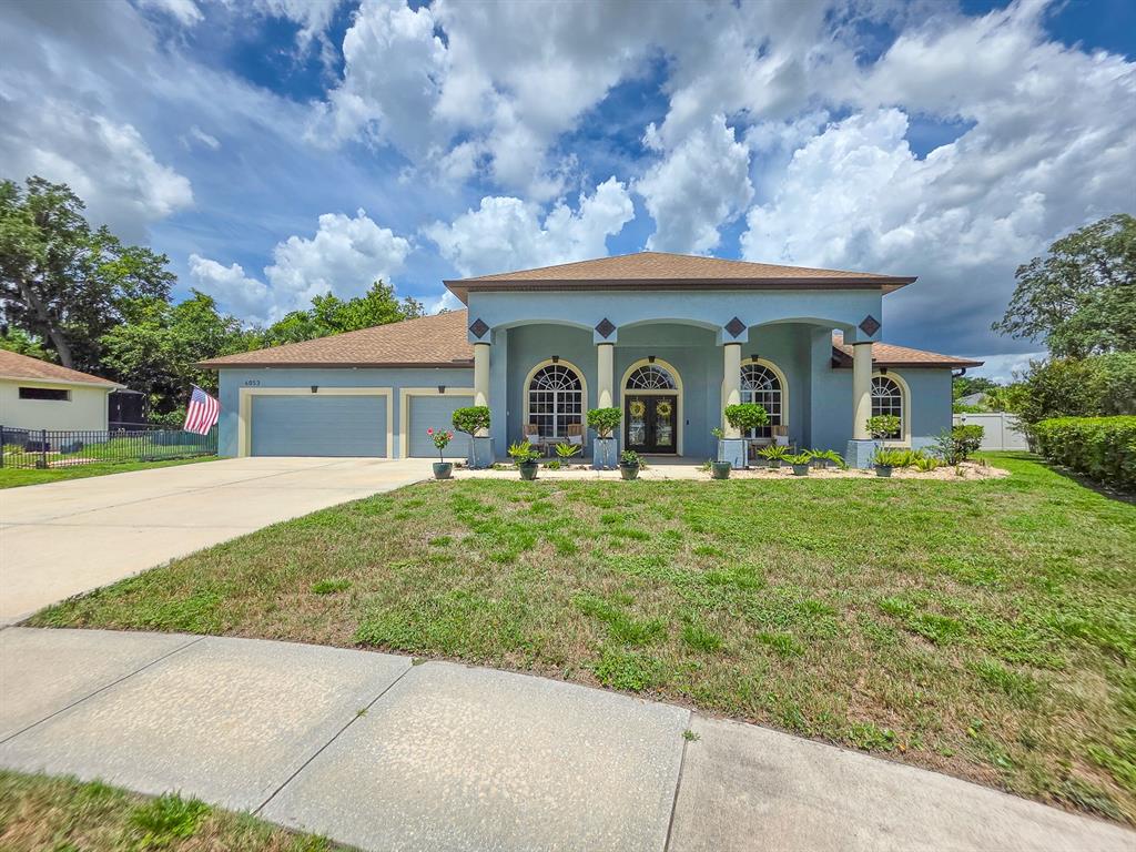 A light blue single-story house features a covered front porch with columns and a garage — 6053 SABAL CREEK BOULEVARD, PORT ORANGE, FL