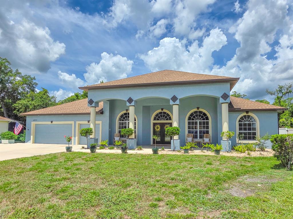 A light blue single-story house features a large covered front porch with arched columns — 6053 SABAL CREEK BOULEVARD, PORT ORANGE, FL
