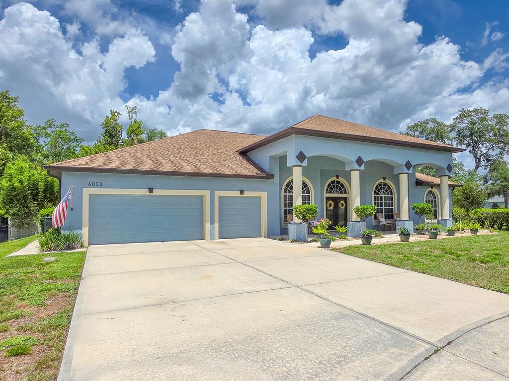 A blue single-story house with a three-car garage and a covered front porch with columns — 6053 SABAL CREEK BOULEVARD, PORT ORANGE, FL
